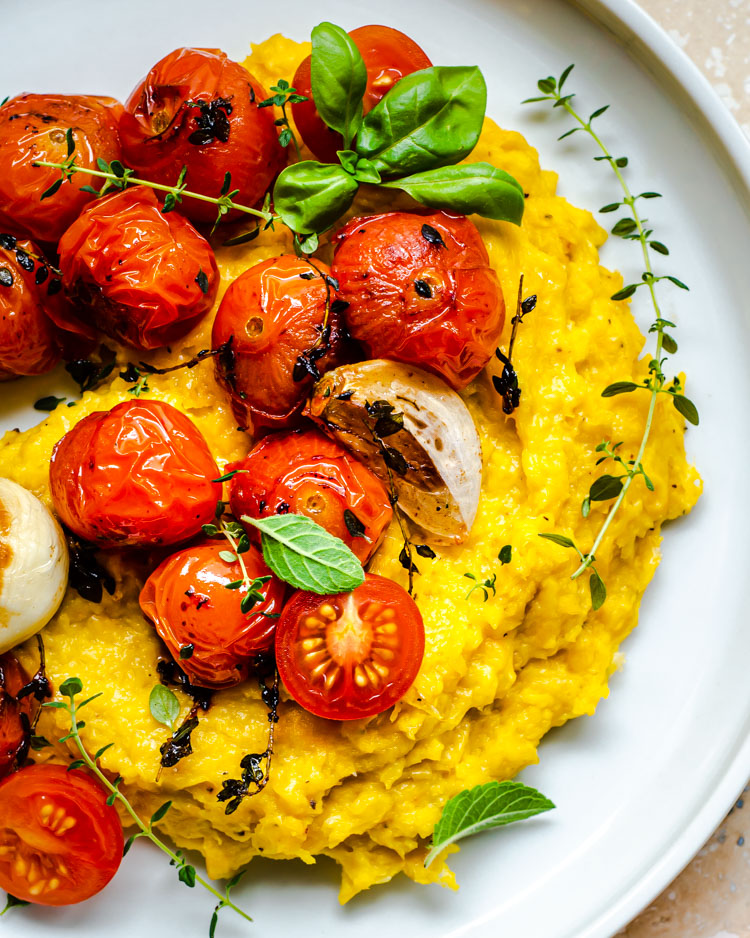 Polenta with roasted tomatoes on white plate